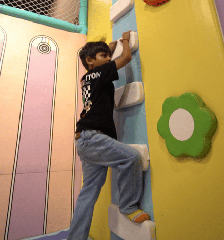 Child climbing an indoor rock climbing wall at Wooray Patna play area.