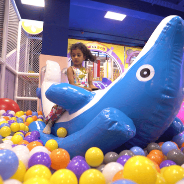 Child enjoying an inflatable whale ride in the colourful ball pit at Wooray Patna.
