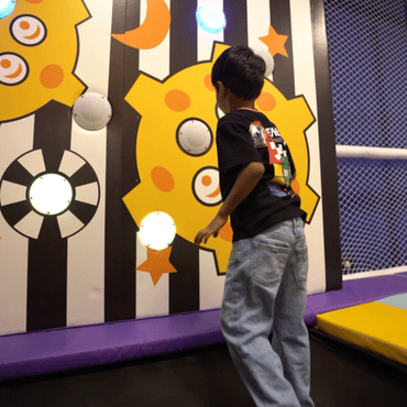Child enjoying an interactive wall game in the indoor play area at Wooray Patna.