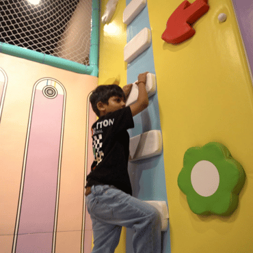 Child climbing an indoor rock climbing wall at Wooray Patna play area.
